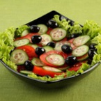 Салата от домати, краставици и маслини върху подложка от зелена салатка